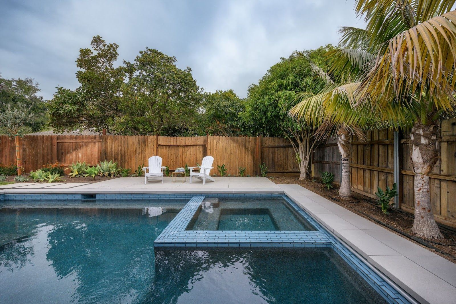 Fluidity pool design with spa and tropical backyard patio